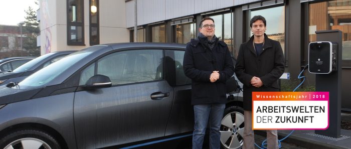 Zwei Personen vor Elektroauto an Ladestation