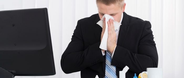 Schneuzender Mann am Schreibtisch
