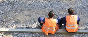 Zwei Straßenarbeiter mit Migrationshuntergrund sitzen auf einer „unfertigen“ Straße und machen Pause.