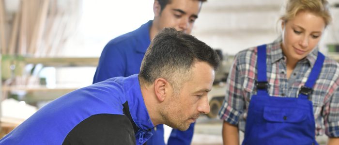 Meister mit zwei Auszubildenden in einer Werkstatt