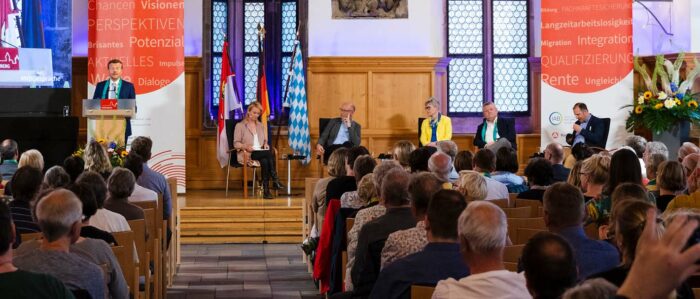 Zu sehen ist das Podium während der Begrüßungsrede von Oberbürgermeister Markus König mit allen Gesprächsteilnehmern und vielen Gästen.