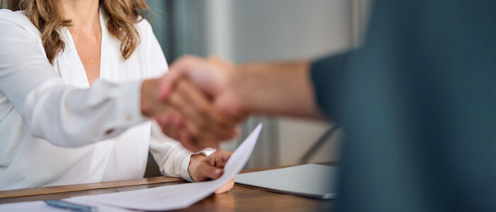 Junge Frau beim Handschlag mit dem Vertragspartner.