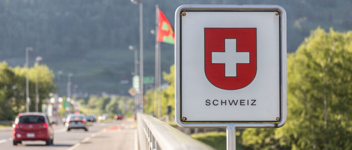 Autos fahren auf einer Straße über die Schweizer Grenze.