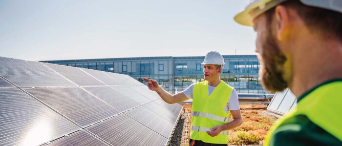 Two technicians on a roof in front of a solar module
