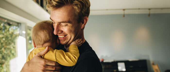 Lächelnder Vater hält zu Hause sein Kleinkind auf dem Arm.