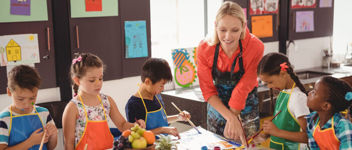 Teacher assisting schoolkids in drawing class