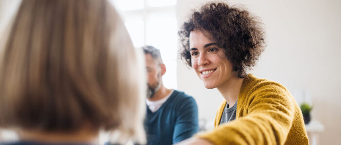 Frau legt ihre Hand auf die Schulter einer anderen Frau in einer Gruppensituation.