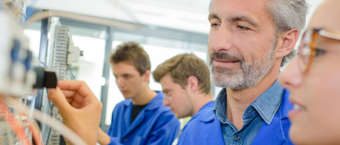 Lehrlinge und Meister an einer elektrischen Anlage.