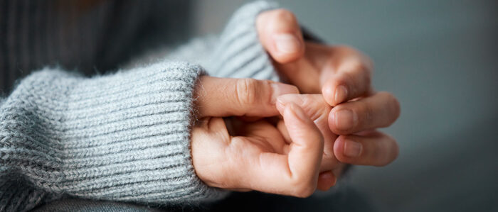 Nahaufnahme von den Händen einer Frau. Die Haltung der Hände zeigt eine psychische Anspannung