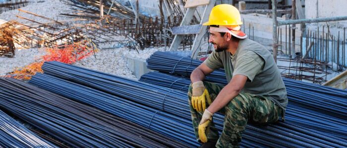 Construction worker resting on concrete reinforcing bars.